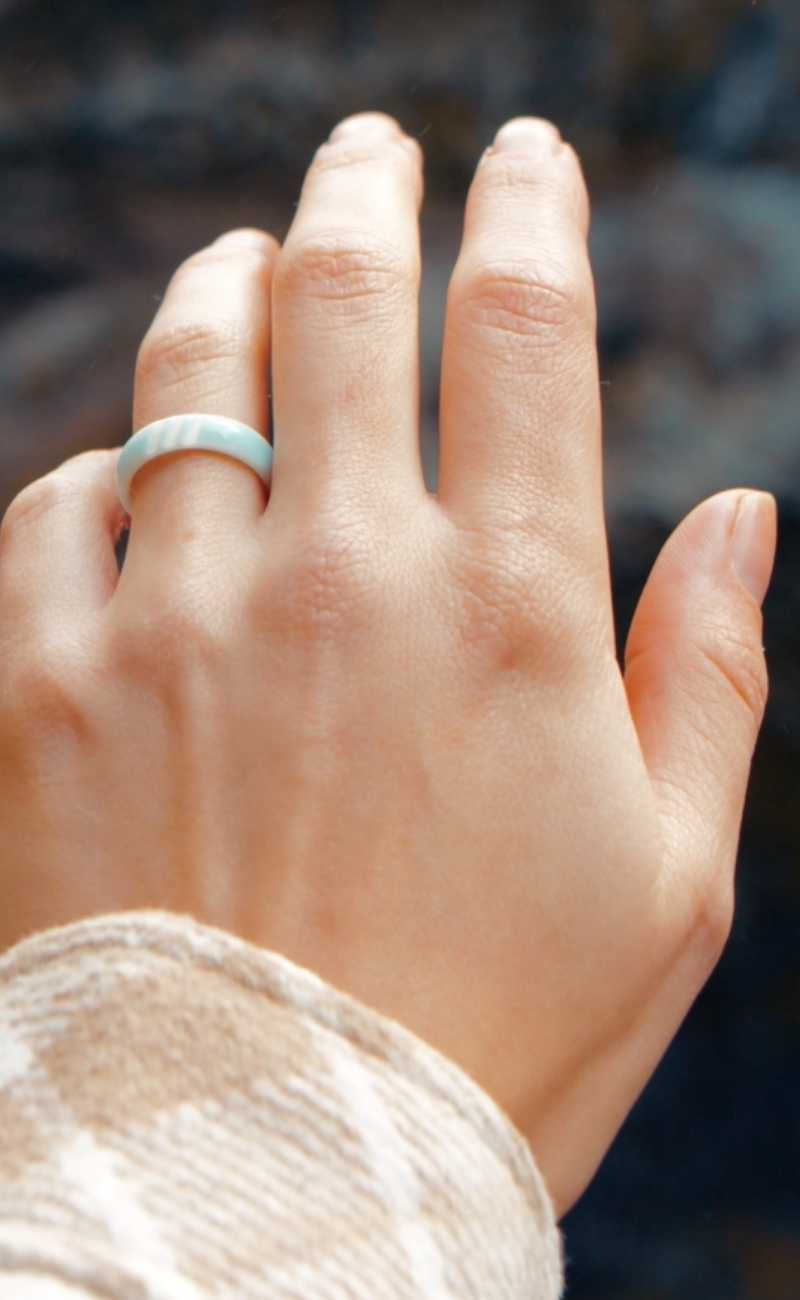 a women's hand in the air wearing silicone rings.