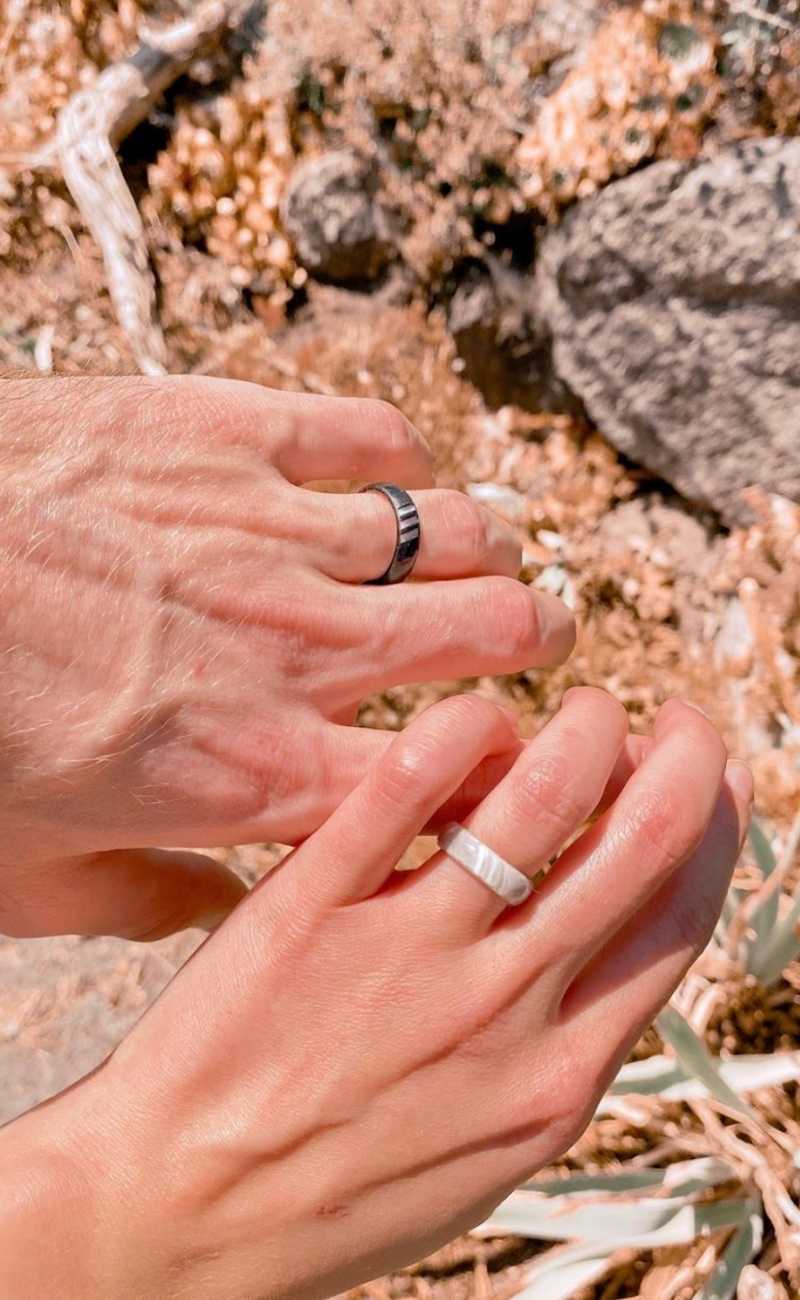 a couple holding their hands out showing their silicone rings. 