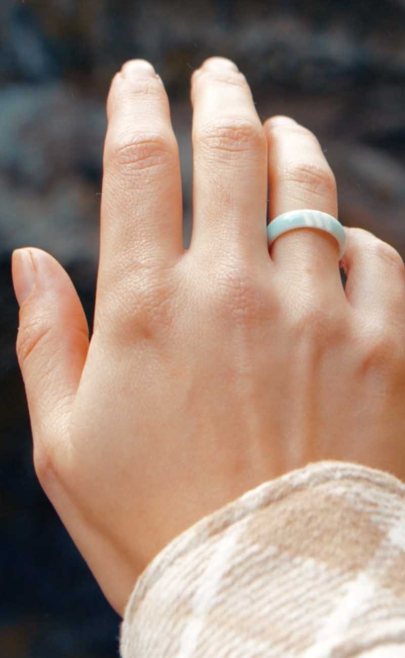 a women's hand in the air wearing silicone rings. 