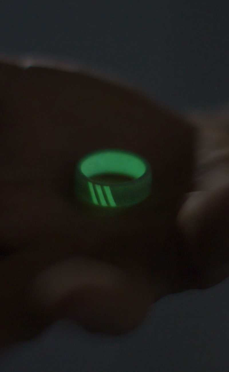 a silicone ring glowing in the dark in the palm of a persons hand. 