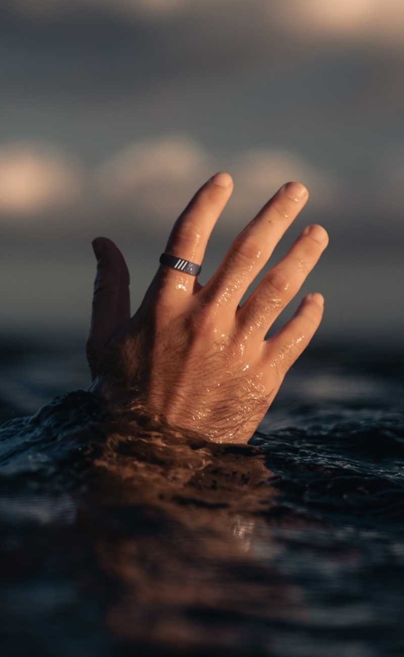 A mans hand in the ocean wearing a silicone ring. 